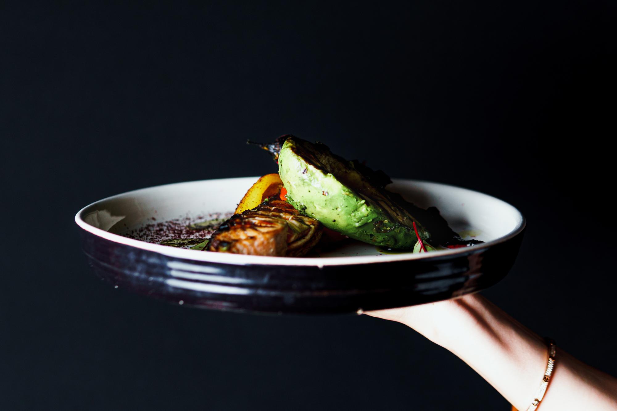 Chef plating a modern dish on dark table